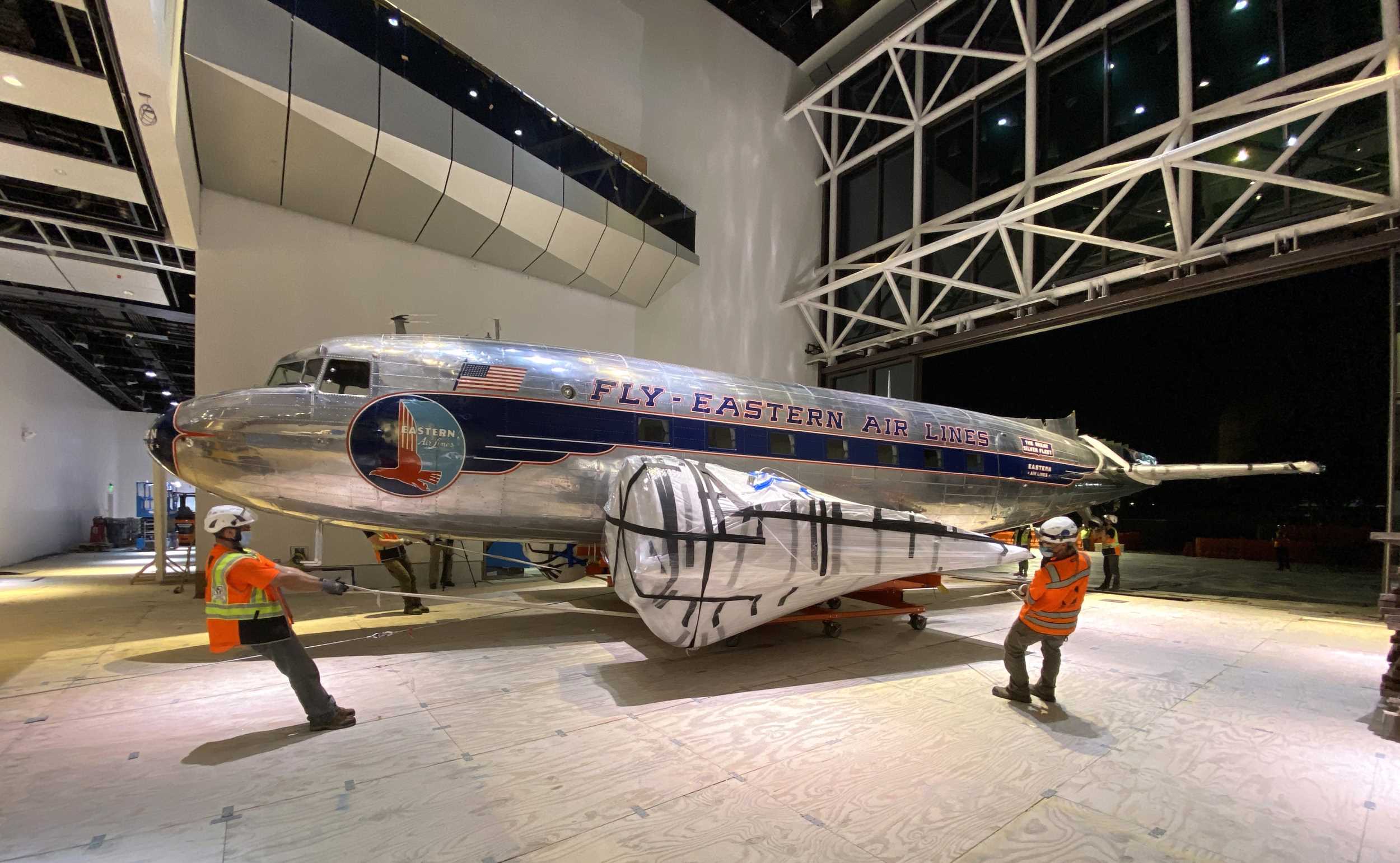 An airplane enters museum building through hangar door on west end. My role was to coordinate with site superintendents to clear a path for artifacts to travel through the active construction site.